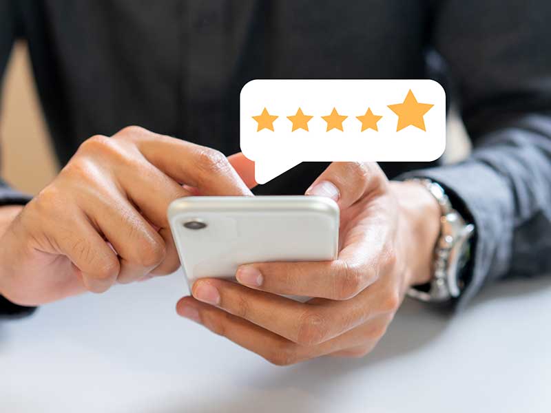 Close up of a person's hands leaving a 5-star review on their phone